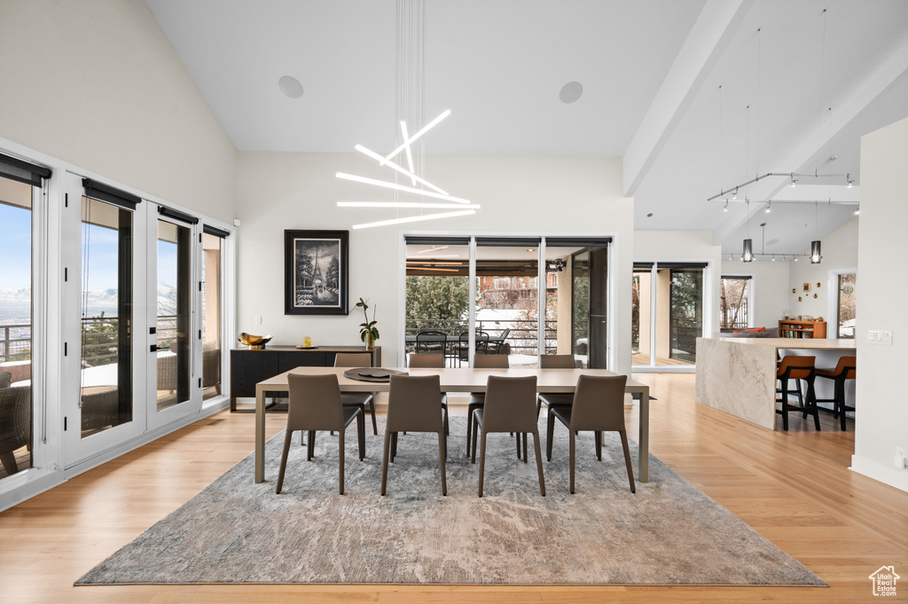 Dining room featuring high vaulted ceiling, light hardwood / wood-style floors, french doors, and an inviting chandelier
