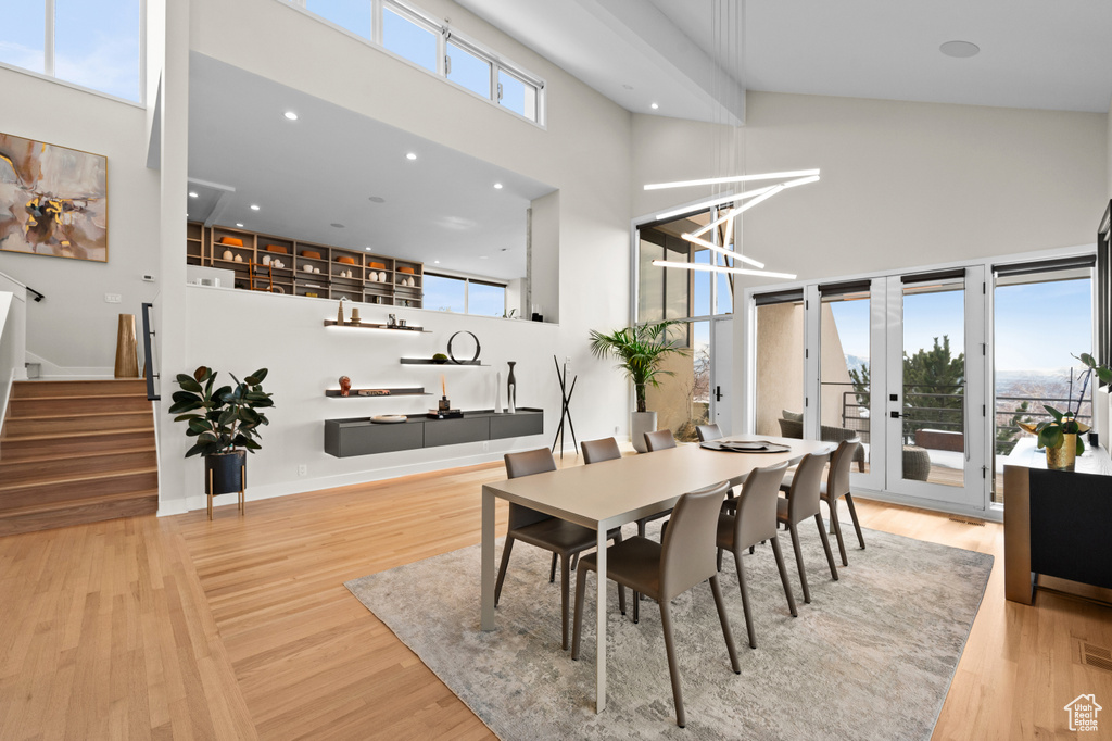 Dining space featuring a towering ceiling, light hardwood / wood-style floors, and french doors