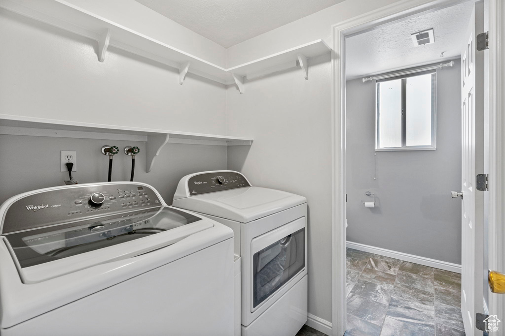 Laundry room featuring a textured ceiling, washing machine and dryer, and tile floors