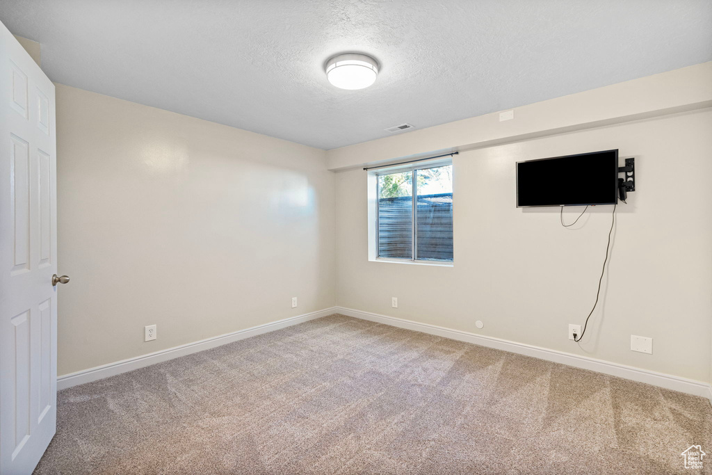 Unfurnished room with a textured ceiling and light carpet