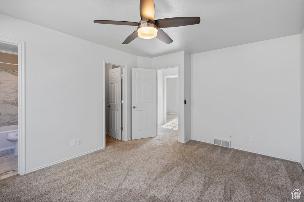 Unfurnished bedroom with ceiling fan, light carpet, and ensuite bath