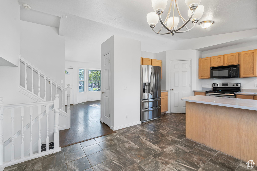 Kitchen featuring decorative light fixtures, an inviting chandelier, light brown cabinets, appliances with stainless steel finishes, and dark tile flooring