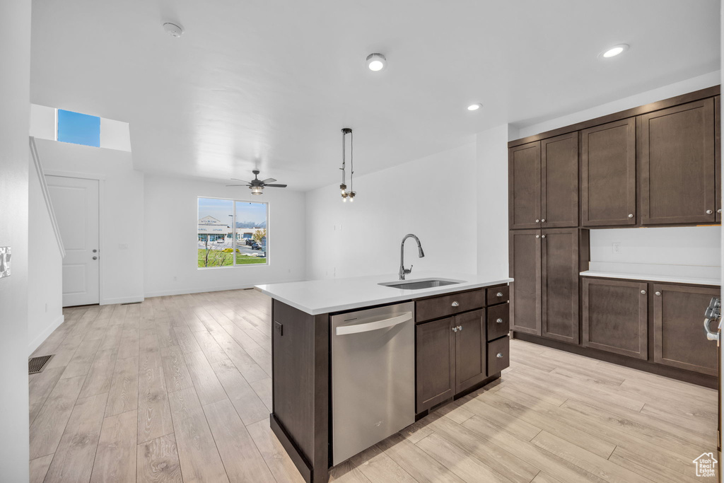 Kitchen with sink, a center island with sink, stainless steel dishwasher, light hardwood / wood-style floors, and ceiling fan