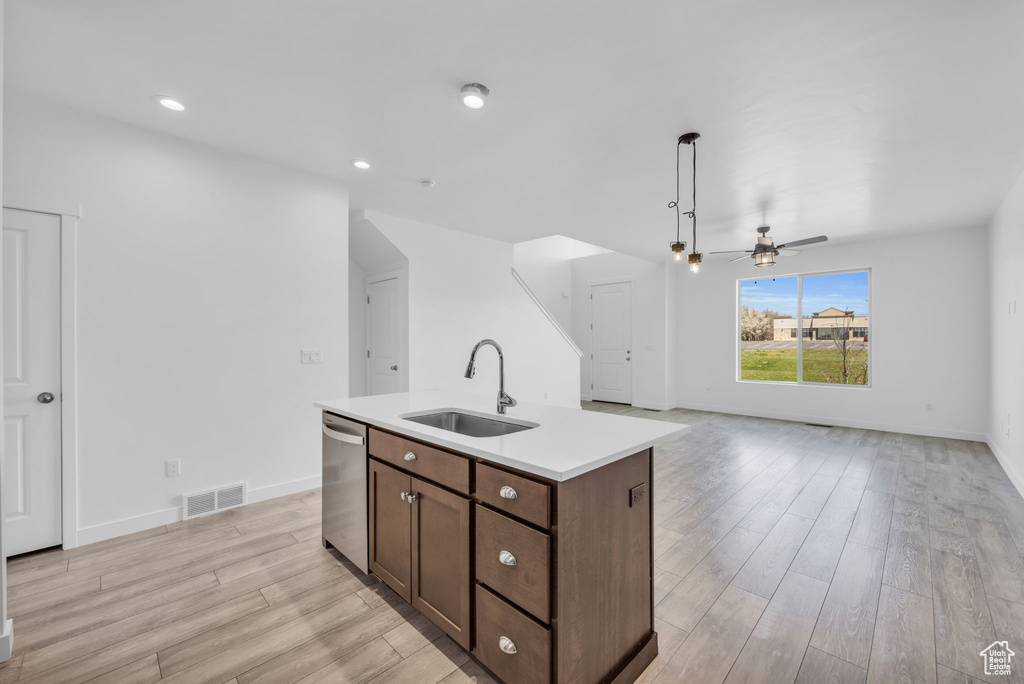 Kitchen with ceiling fan, light hardwood / wood-style flooring, sink, stainless steel dishwasher, and a center island with sink