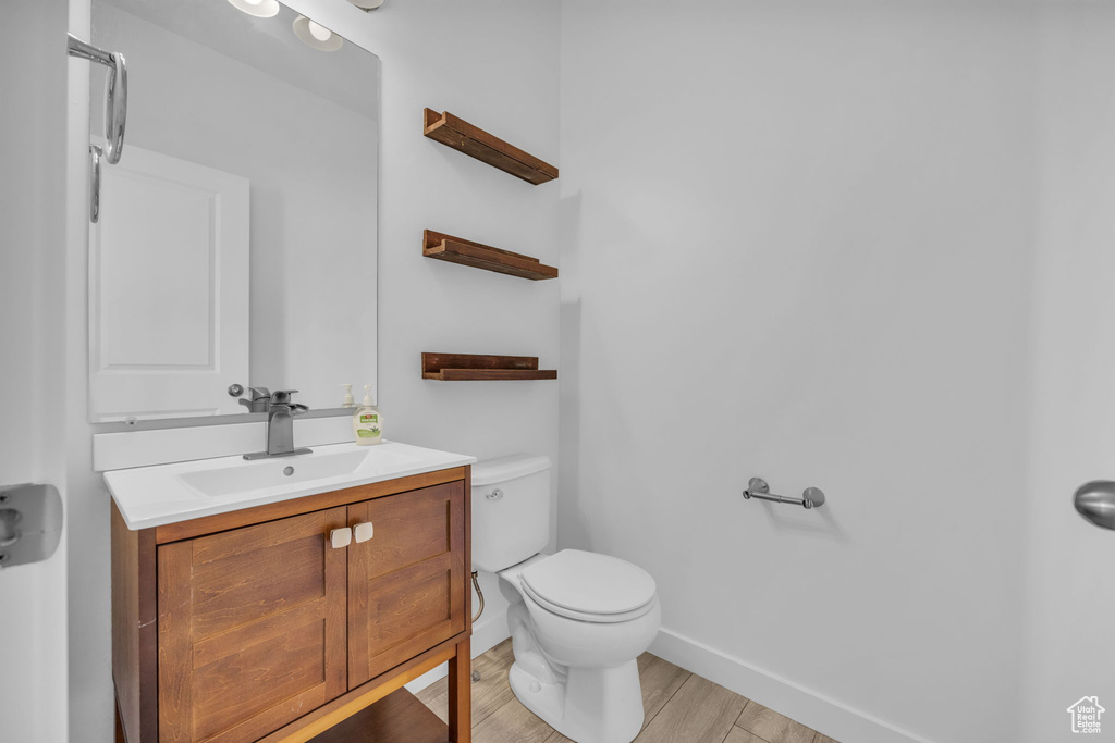 Bathroom featuring wood-type flooring, vanity, and toilet