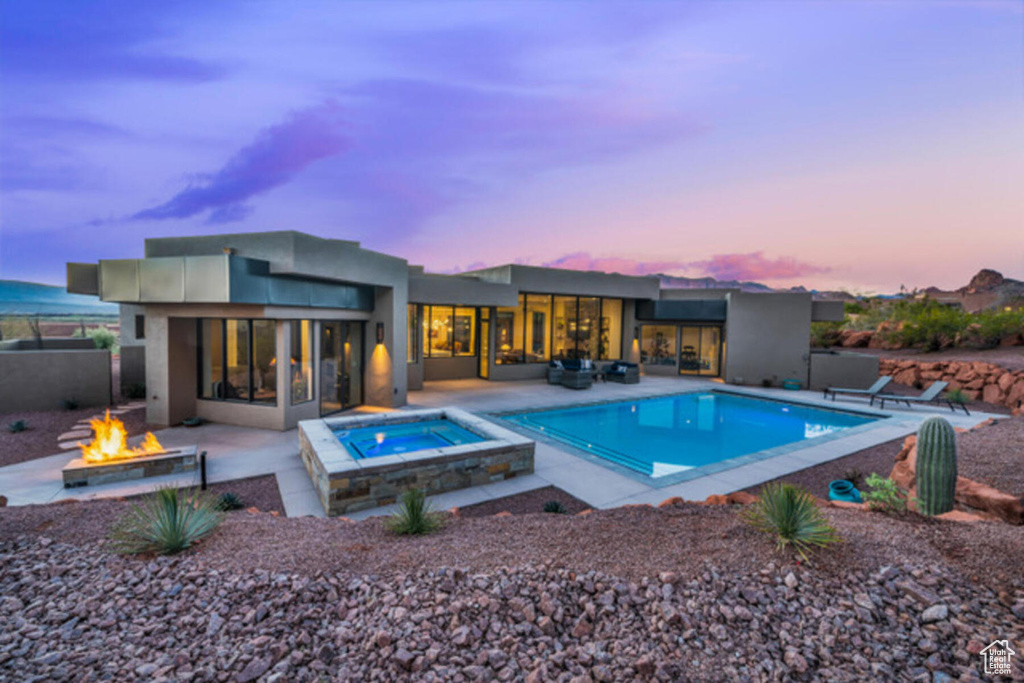 Pool at dusk with an in ground hot tub, a fire pit, and a patio area