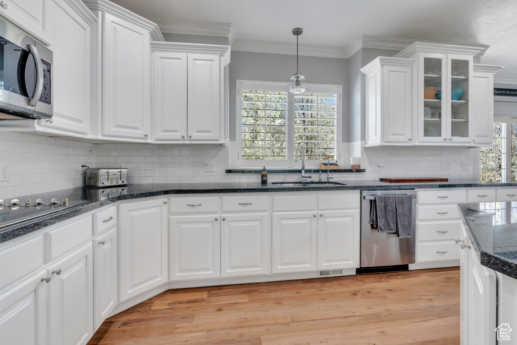 Kitchen with backsplash, light hardwood / wood-style flooring, stainless steel appliances, and white cabinetry