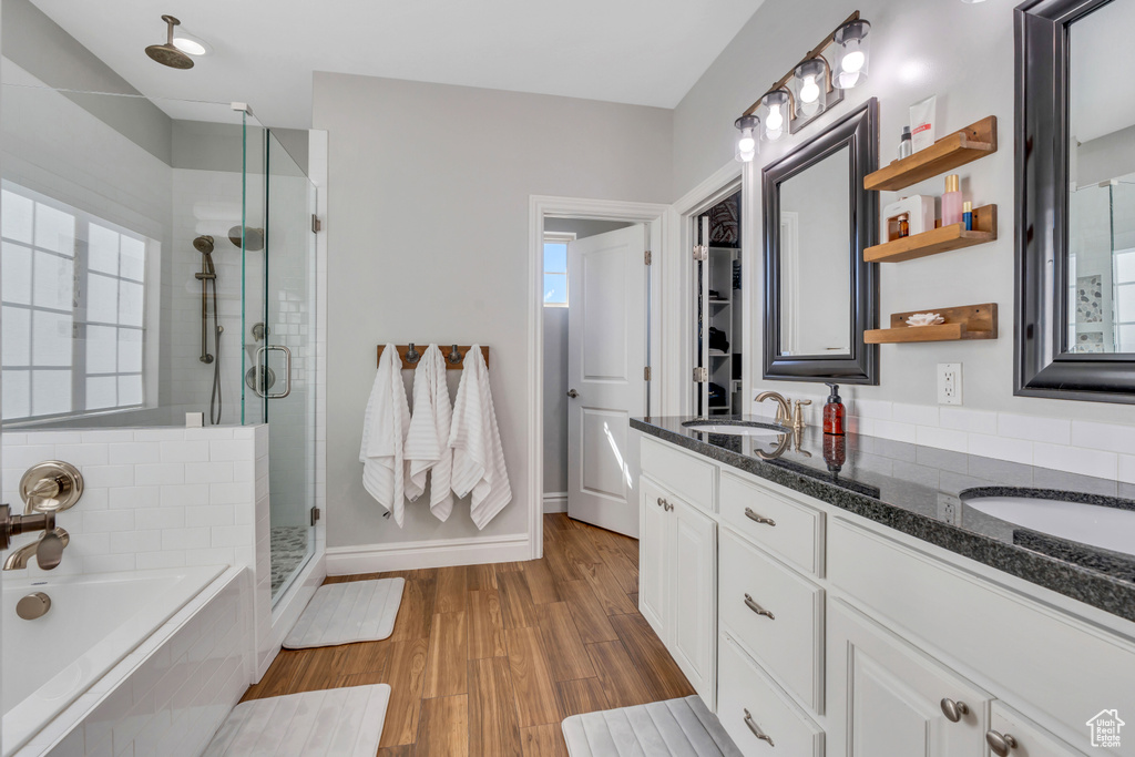 Bathroom with hardwood / wood-style floors, double sink vanity, a healthy amount of sunlight, and separate shower and tub