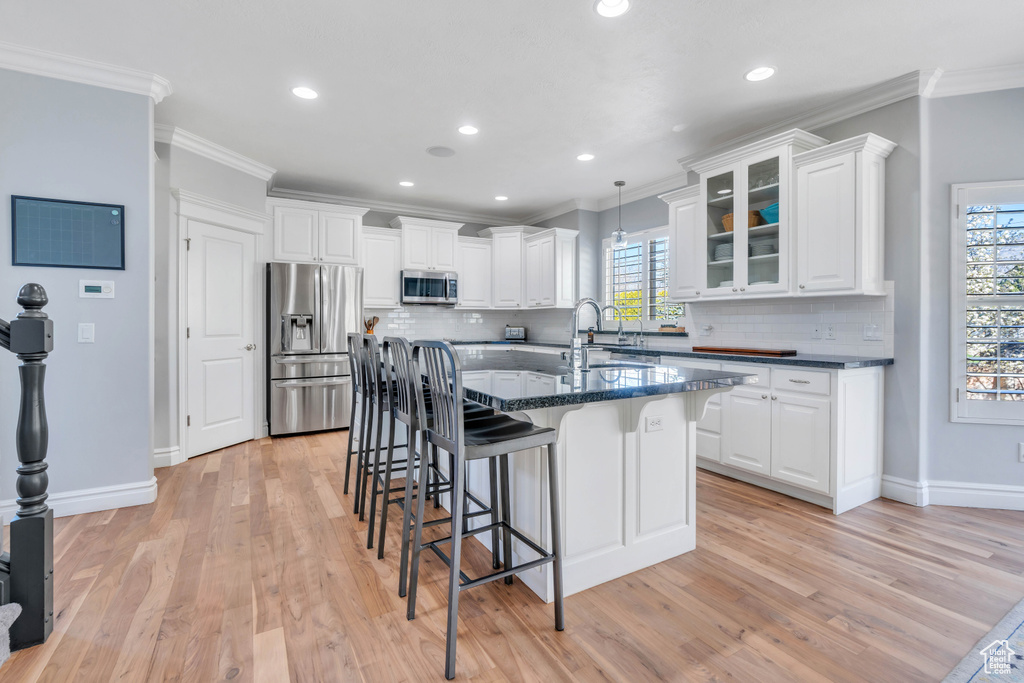 Kitchen with a healthy amount of sunlight, hanging light fixtures, stainless steel appliances, and light wood-type flooring