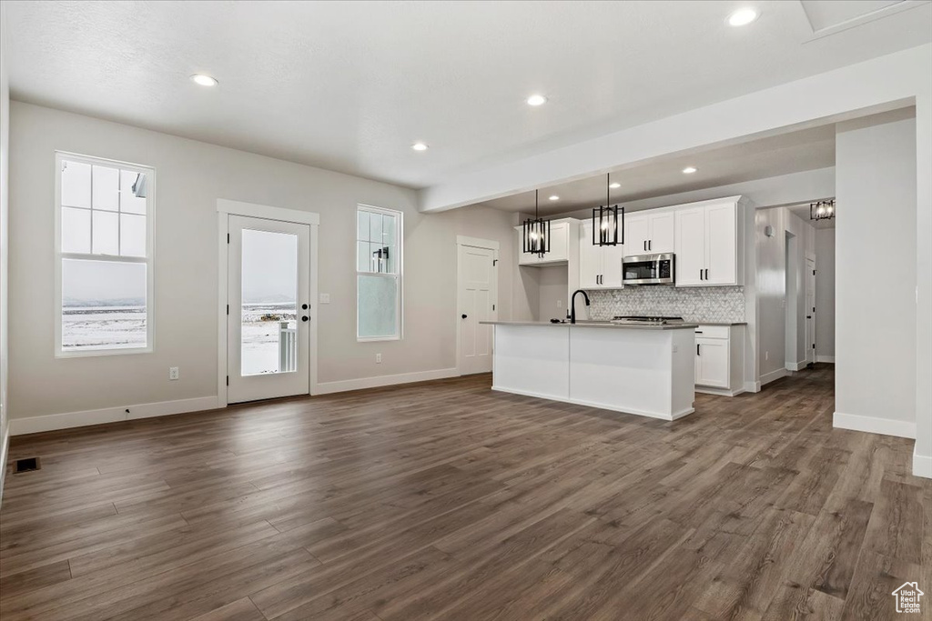 Kitchen with dark hardwood / wood-style floors, white cabinetry, and a center island with sink