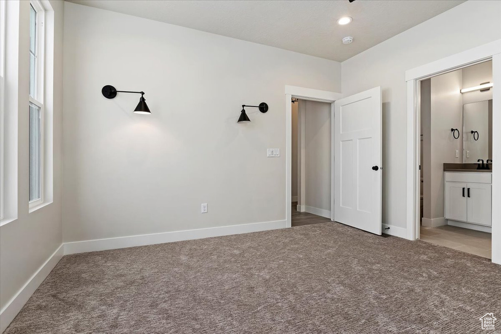 Unfurnished bedroom featuring connected bathroom and dark colored carpet