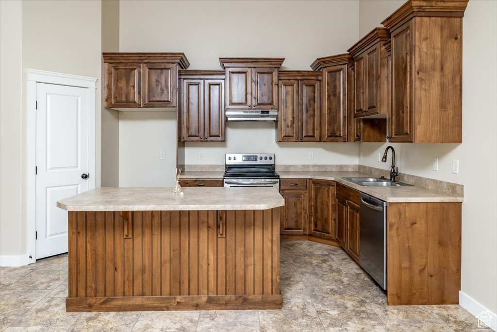 Kitchen with appliances with stainless steel finishes, a kitchen bar, light tile floors, a center island, and sink
