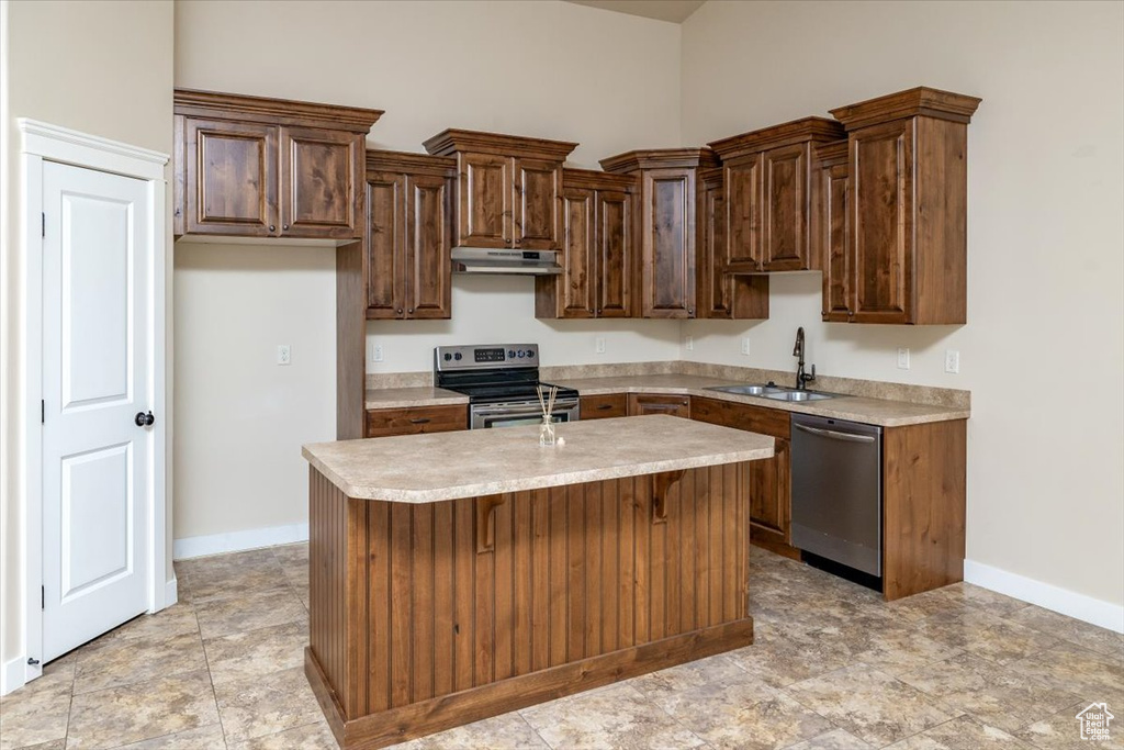 Kitchen with a breakfast bar area, a center island with sink, stainless steel appliances, sink, and light tile flooring
