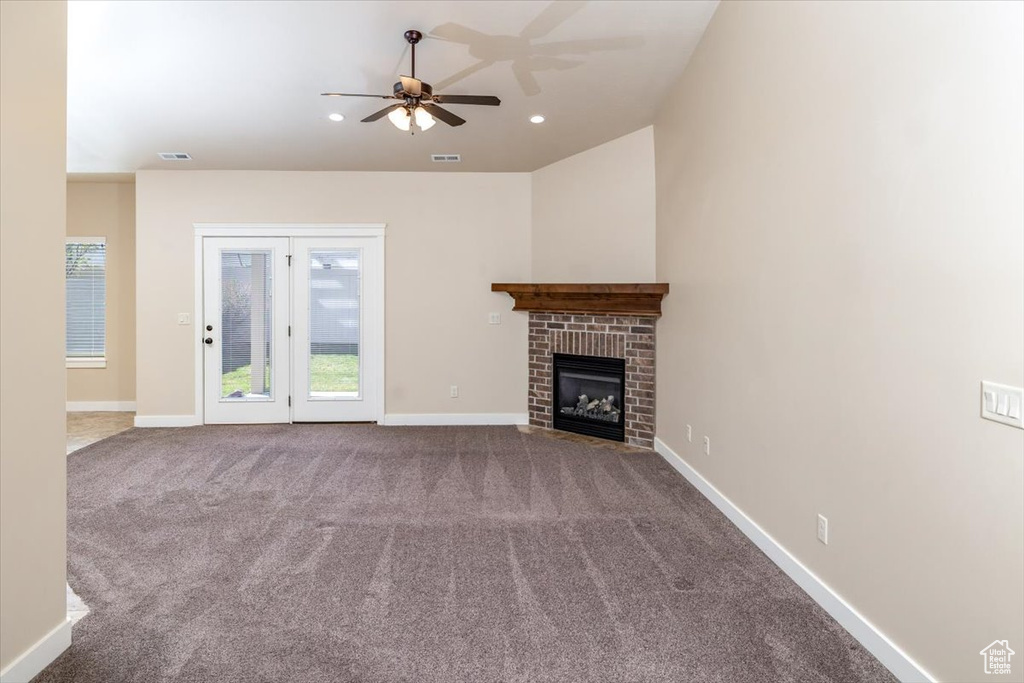 Unfurnished living room with ceiling fan, a fireplace, and dark carpet