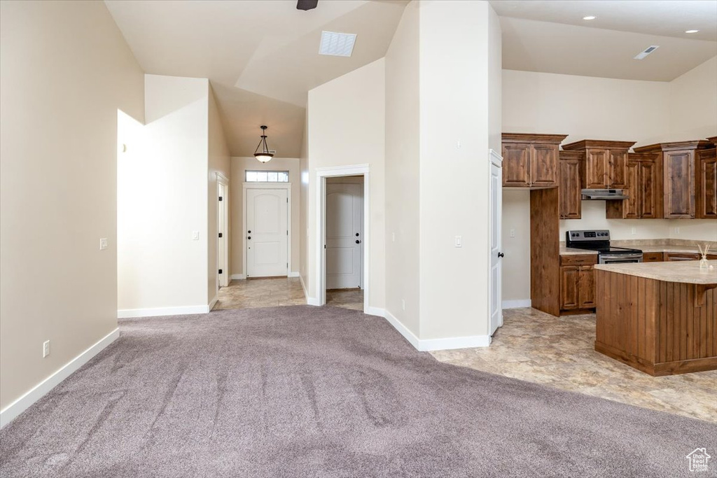 Kitchen featuring high vaulted ceiling, stainless steel electric stove, and light colored carpet