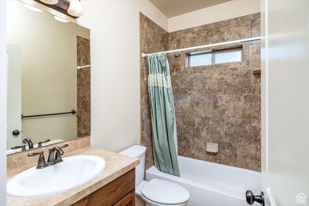 Full bathroom with toilet, shower / bath combination with curtain, and vanity with extensive cabinet space