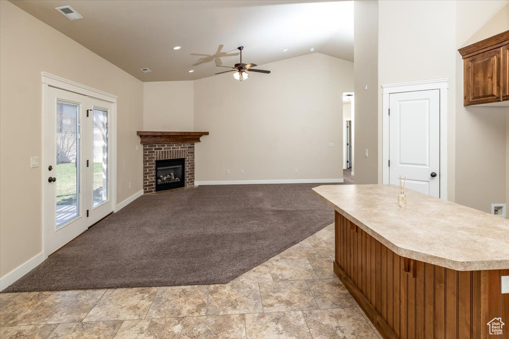 Unfurnished living room featuring ceiling fan, a fireplace, light carpet, and vaulted ceiling