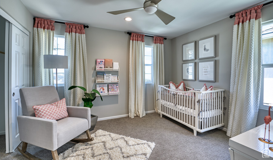 Carpeted bedroom featuring ceiling fan, a nursery area, and a closet