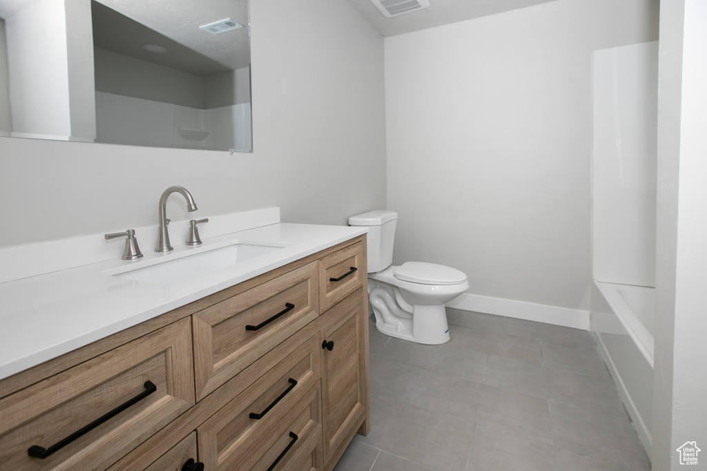 Full bathroom with toilet, large vanity, tile floors, and bathing tub / shower combination