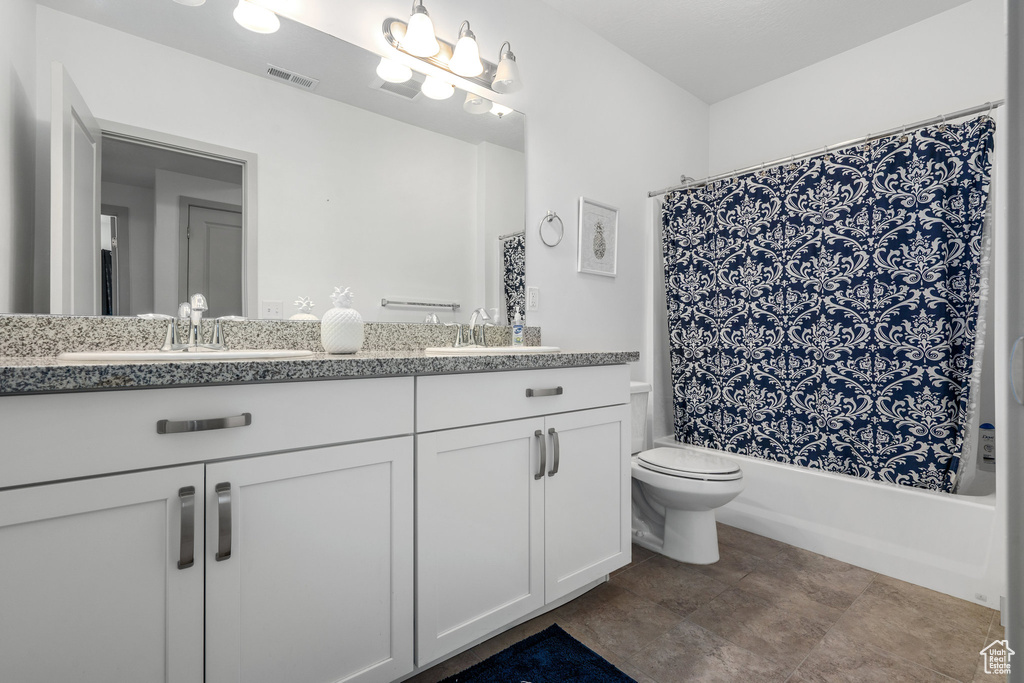 Full bathroom with double sink vanity, toilet, shower / bath combo, and tile floors