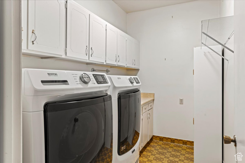 Laundry room with tile flooring, cabinets, and washer and dryer