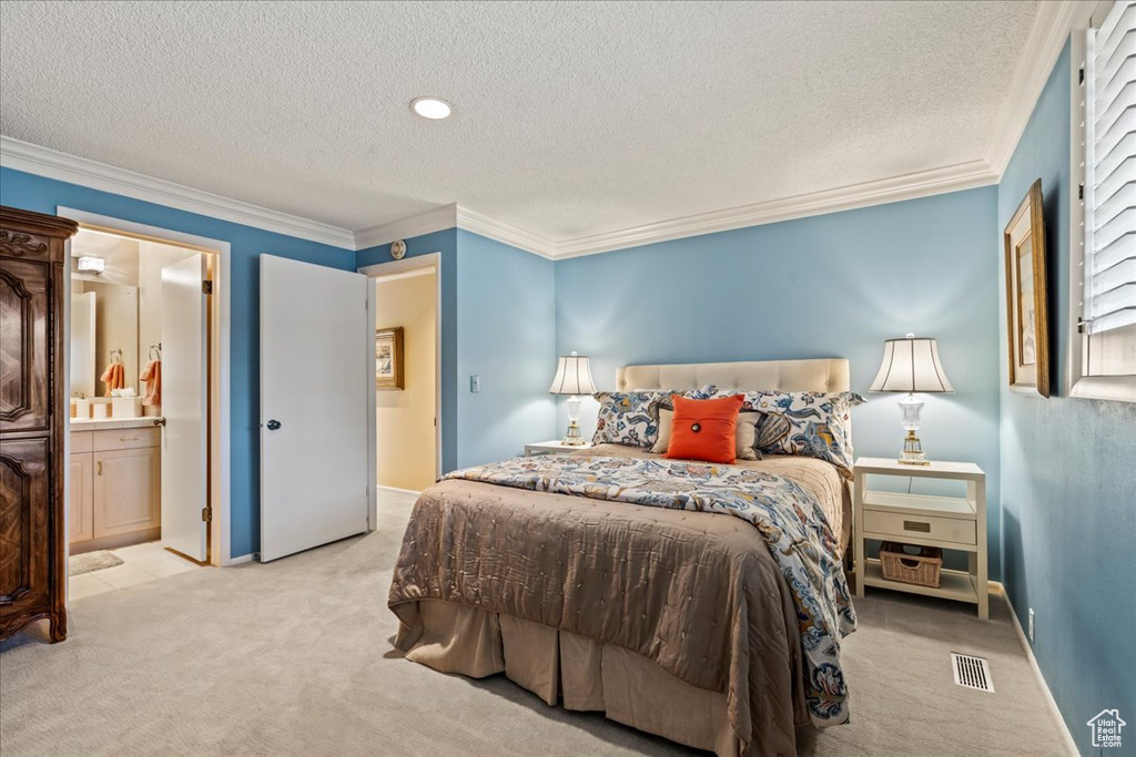 Bedroom with connected bathroom, light colored carpet, ornamental molding, and a textured ceiling