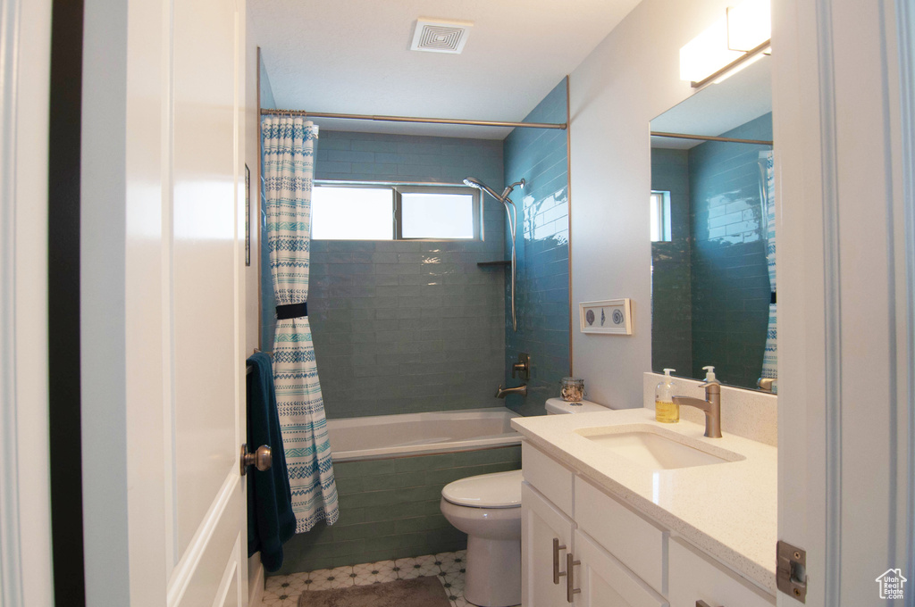 Full bathroom featuring shower / tub combo, vanity with extensive cabinet space, tile flooring, and toilet