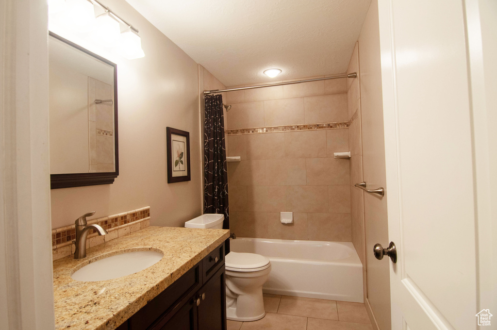 Full bathroom featuring shower / bathtub combination with curtain, tile floors, toilet, and vanity