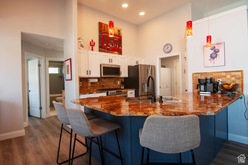 Kitchen featuring dark hardwood / wood-style floors, stainless steel appliances, pendant lighting, and kitchen peninsula