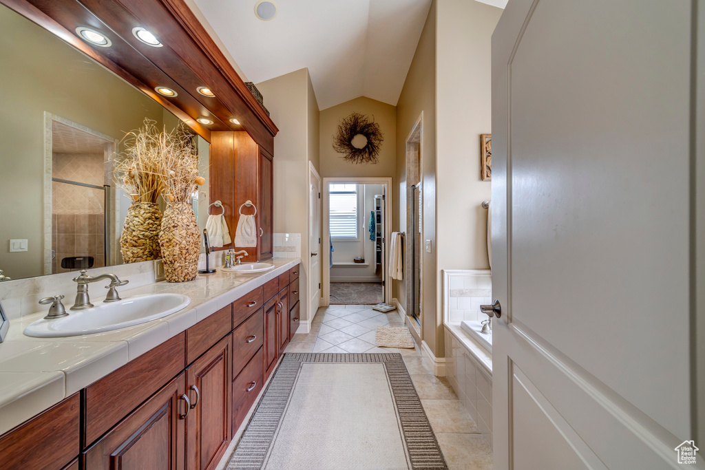Bathroom featuring plus walk in shower, double sink, vanity with extensive cabinet space, and tile flooring