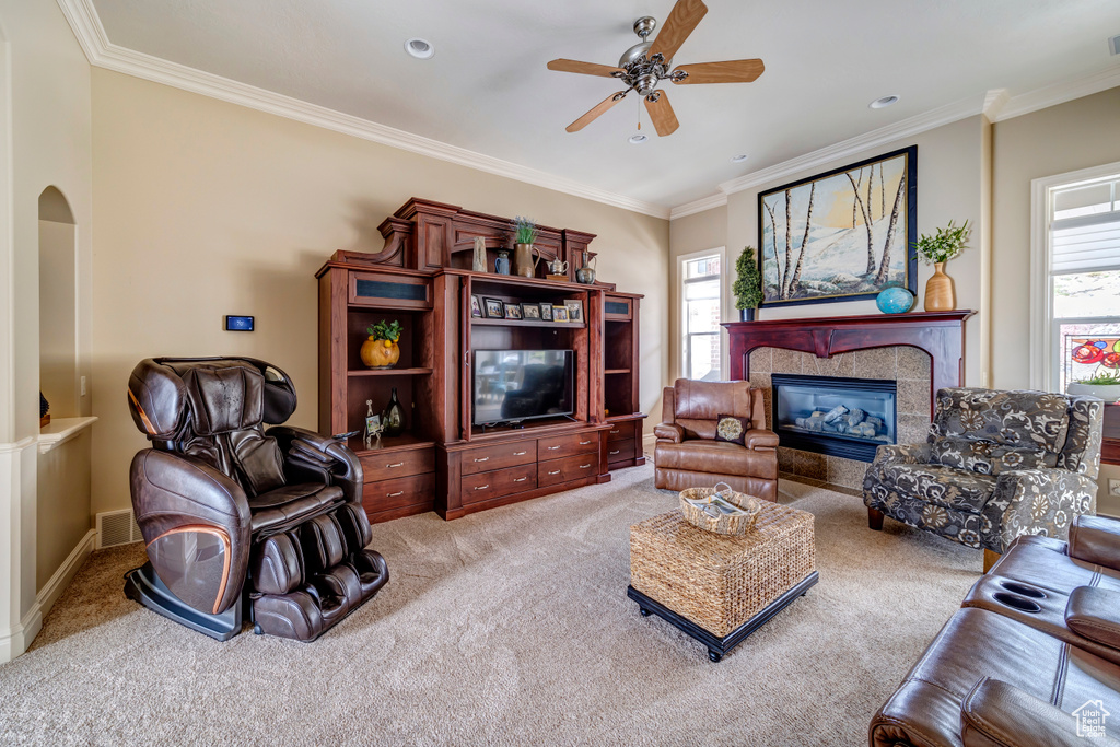 Living room featuring plenty of natural light, ceiling fan, ornamental molding, and light carpet