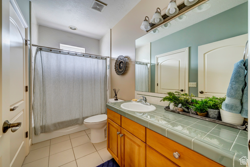Bathroom featuring tile flooring, toilet, oversized vanity, and a textured ceiling
