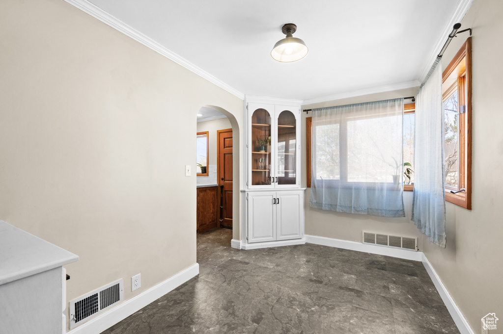 Spare room featuring crown molding and dark tile floors