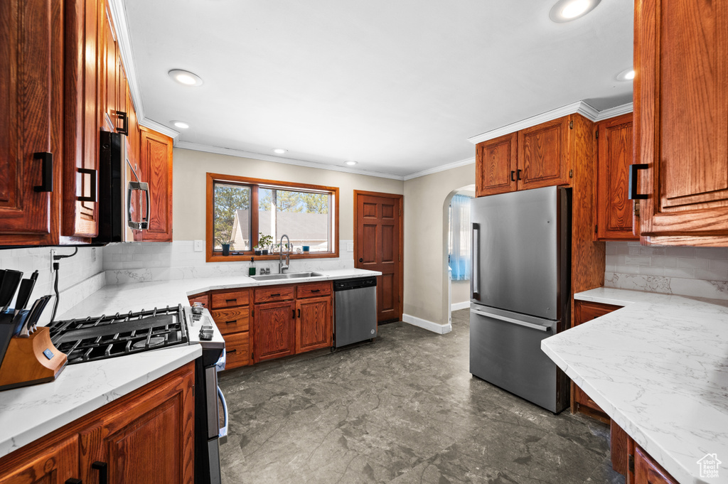 Kitchen with light stone countertops, appliances with stainless steel finishes, tasteful backsplash, and sink
