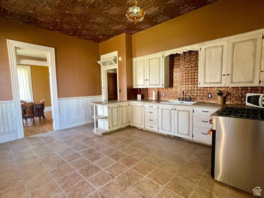 Kitchen with sink, range, tile flooring, and backsplash