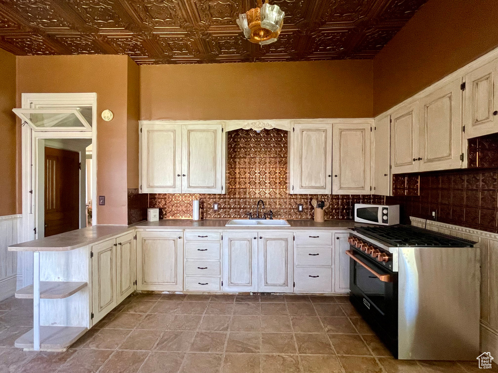 Kitchen featuring range with gas stovetop, light tile floors, tasteful backsplash, and sink