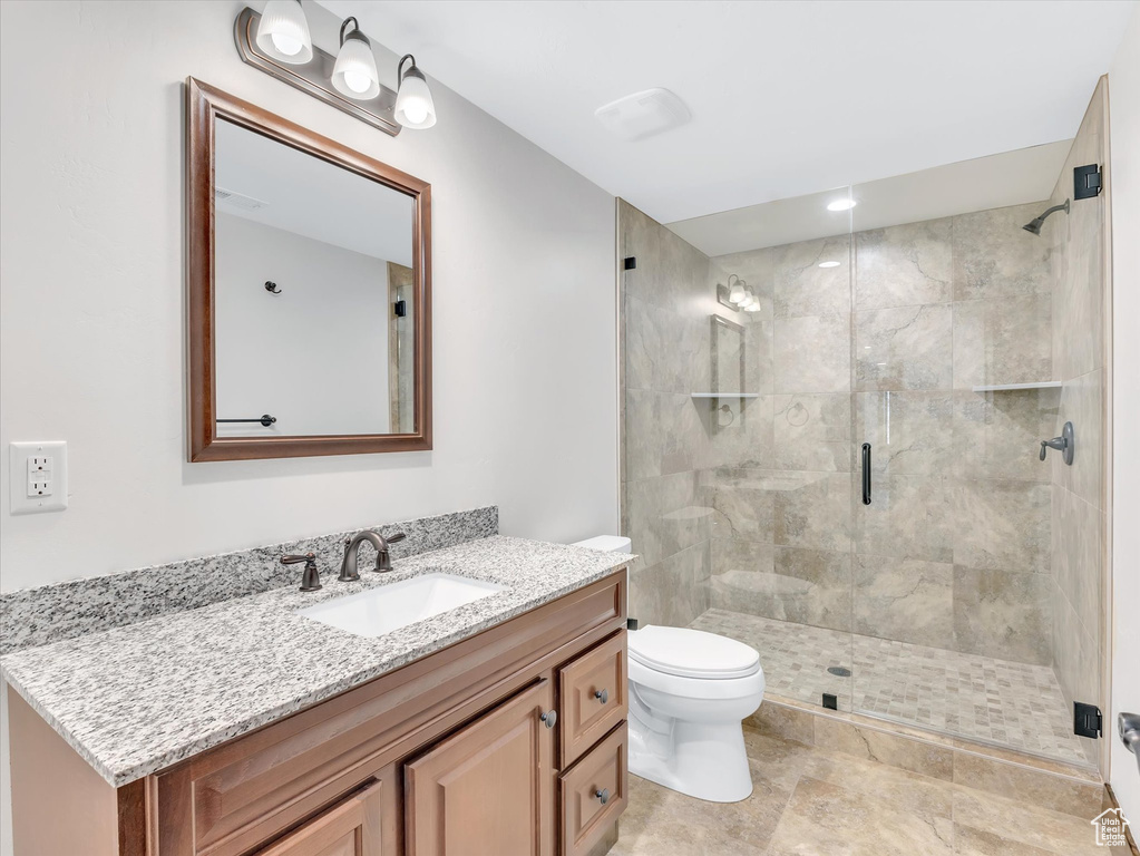 Bathroom with vanity, a stall shower, and toilet