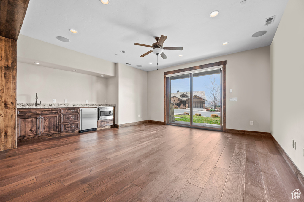 Unfurnished living room featuring ceiling fan, dark hardwood / wood-style floors, and sink