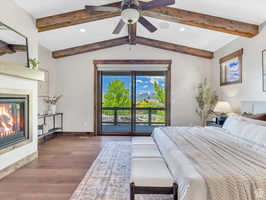 Bedroom with dark wood-style floors, access to outside, a glass covered fireplace, recessed lighting, and baseboards