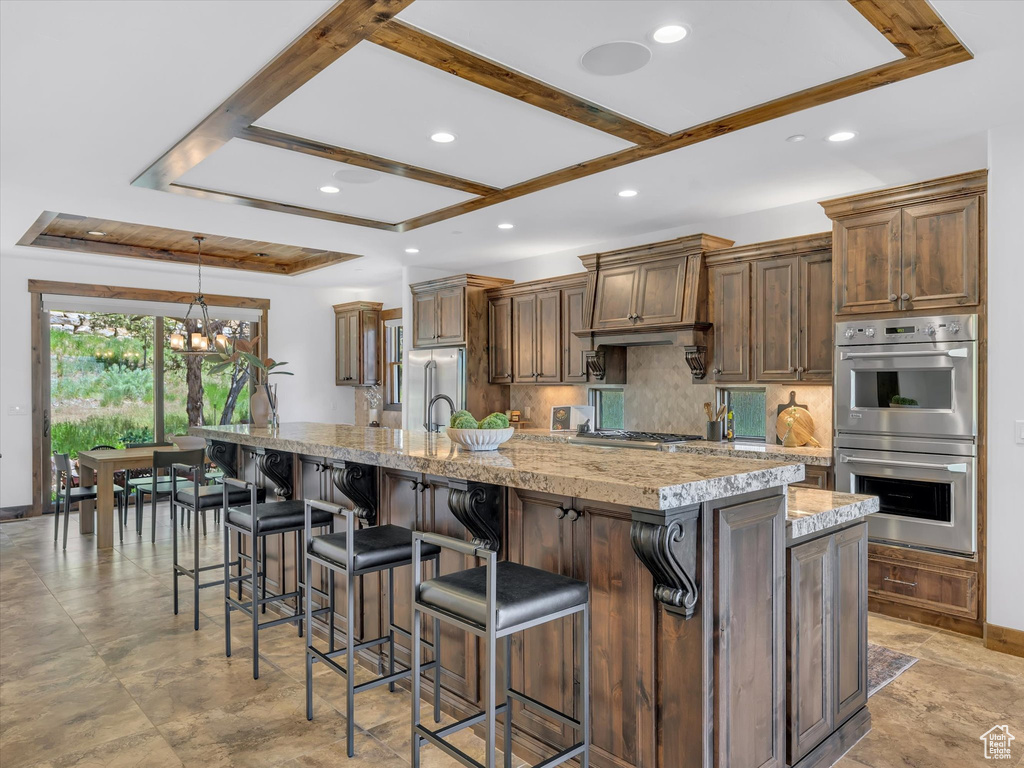 Kitchen featuring stainless steel appliances, recessed lighting, a large island with sink, decorative backsplash, and a chandelier