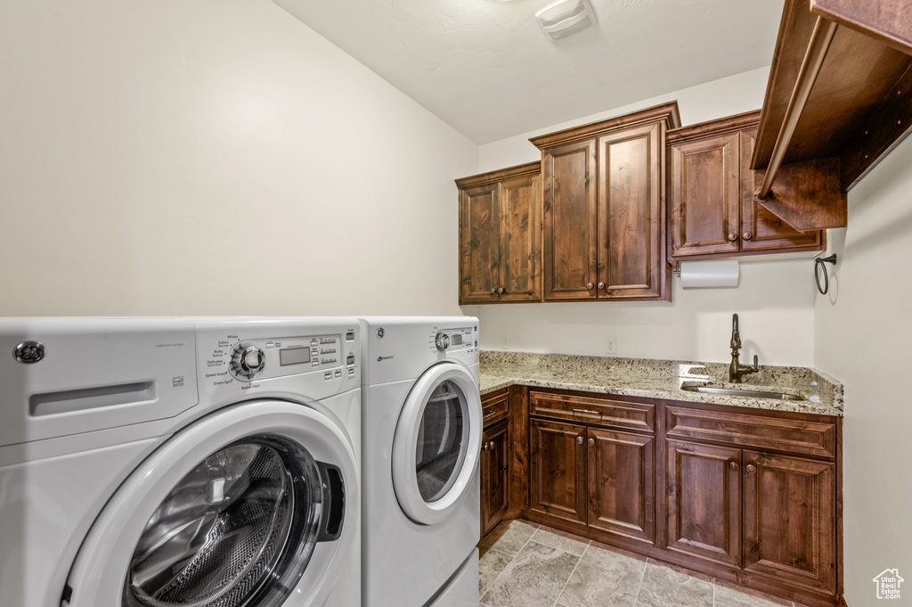 Washroom with separate washer and dryer, sink, light tile flooring, and cabinets