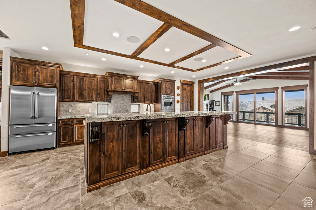 Kitchen featuring ceiling fan, lofted ceiling with beams, appliances with stainless steel finishes, and light tile flooring