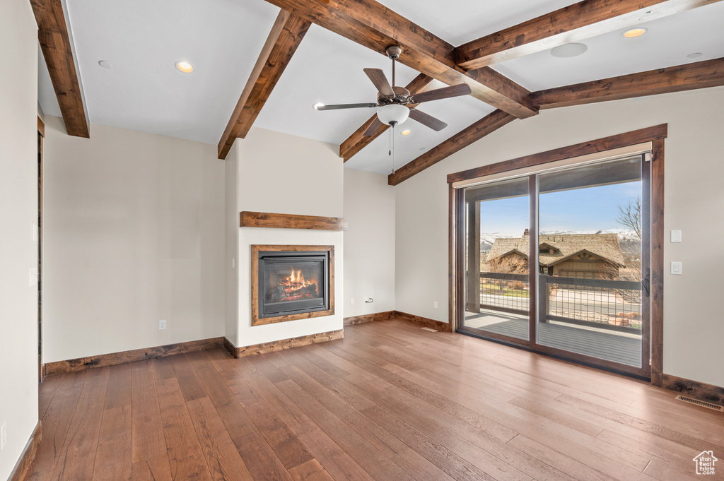 Unfurnished living room featuring ceiling fan, vaulted ceiling with beams, and dark hardwood / wood-style floors
