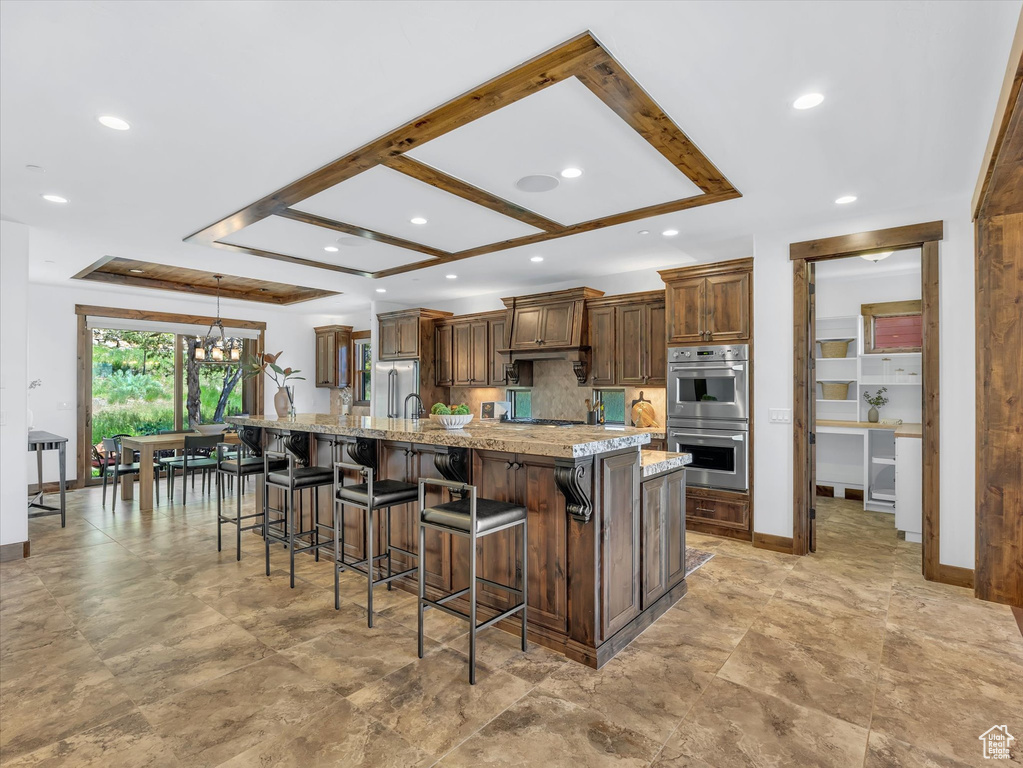 Kitchen with double oven, recessed lighting, a chandelier, a kitchen breakfast bar, and a large island with sink