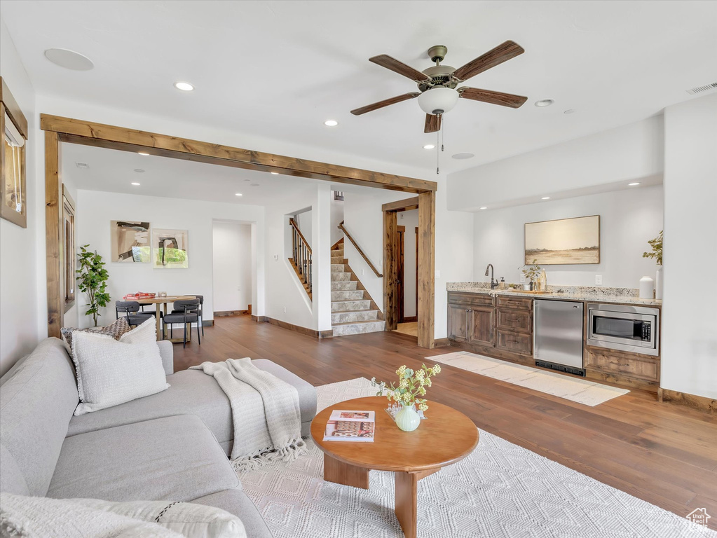 Living area featuring wood finished floors, recessed lighting, wet bar, stairway, and ceiling fan