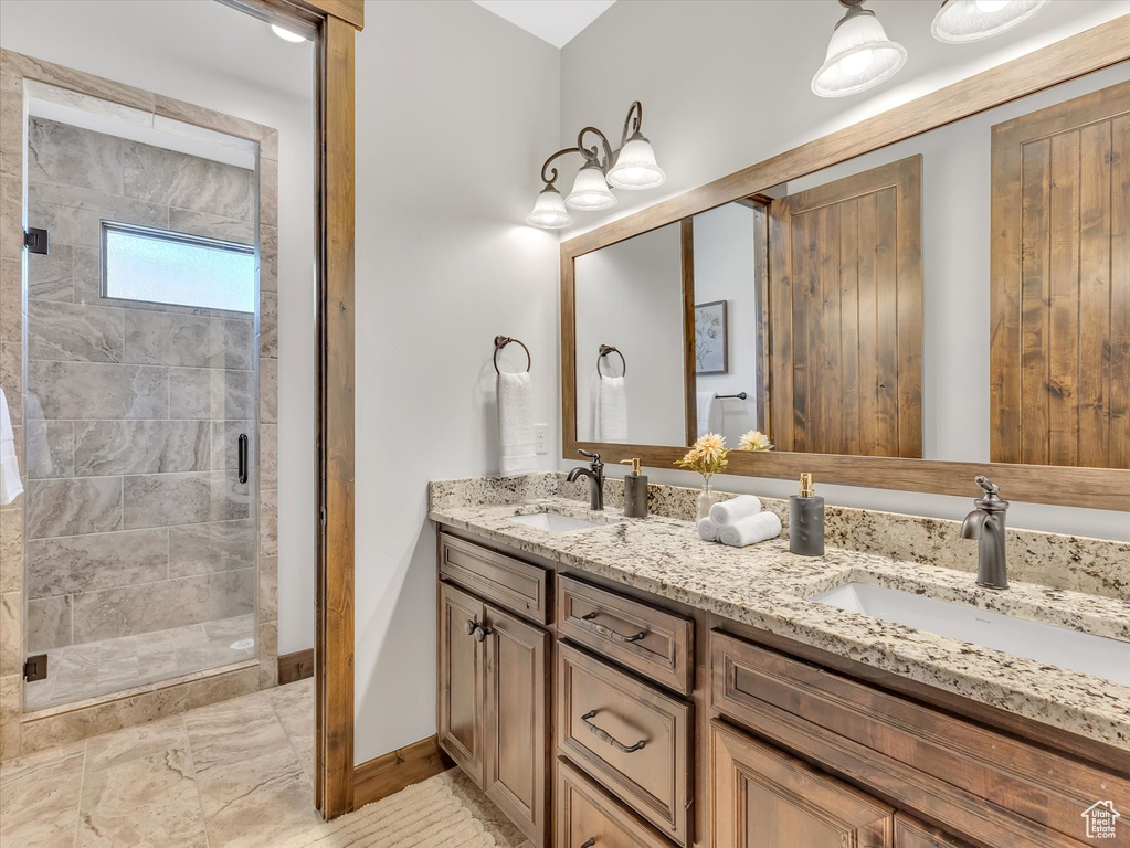 Full bath featuring double vanity, a stall shower, baseboards, and marble finish flooring