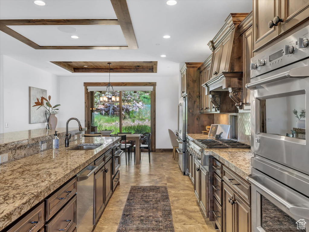 Kitchen with stainless steel appliances, a chandelier, recessed lighting, light stone countertops, and decorative light fixtures