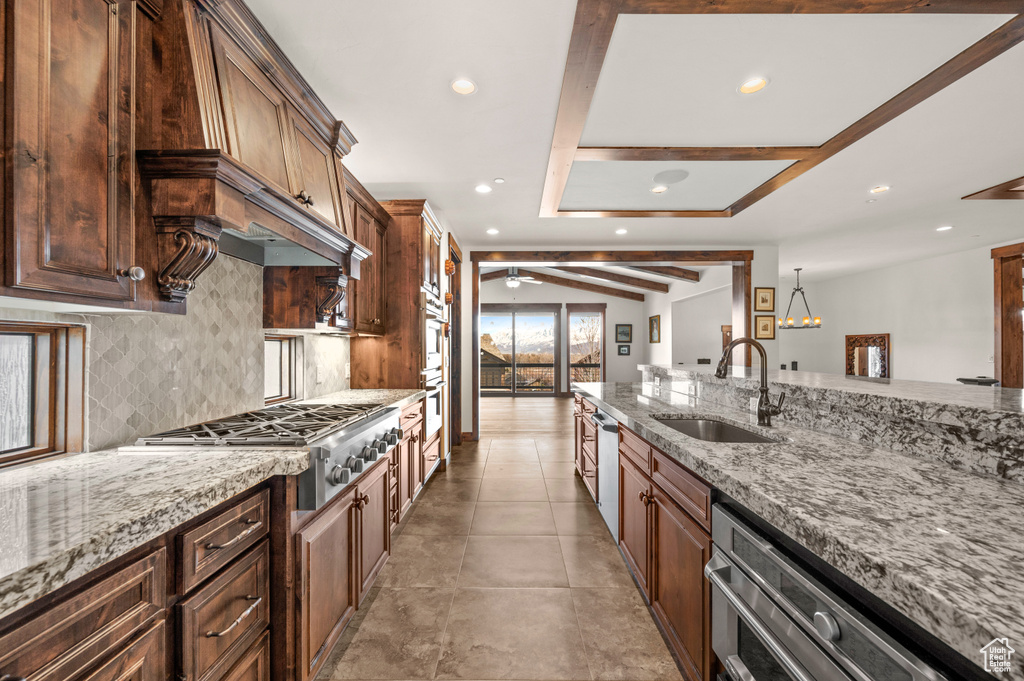 Kitchen featuring appliances with stainless steel finishes, ceiling fan, light tile floors, sink, and light stone countertops