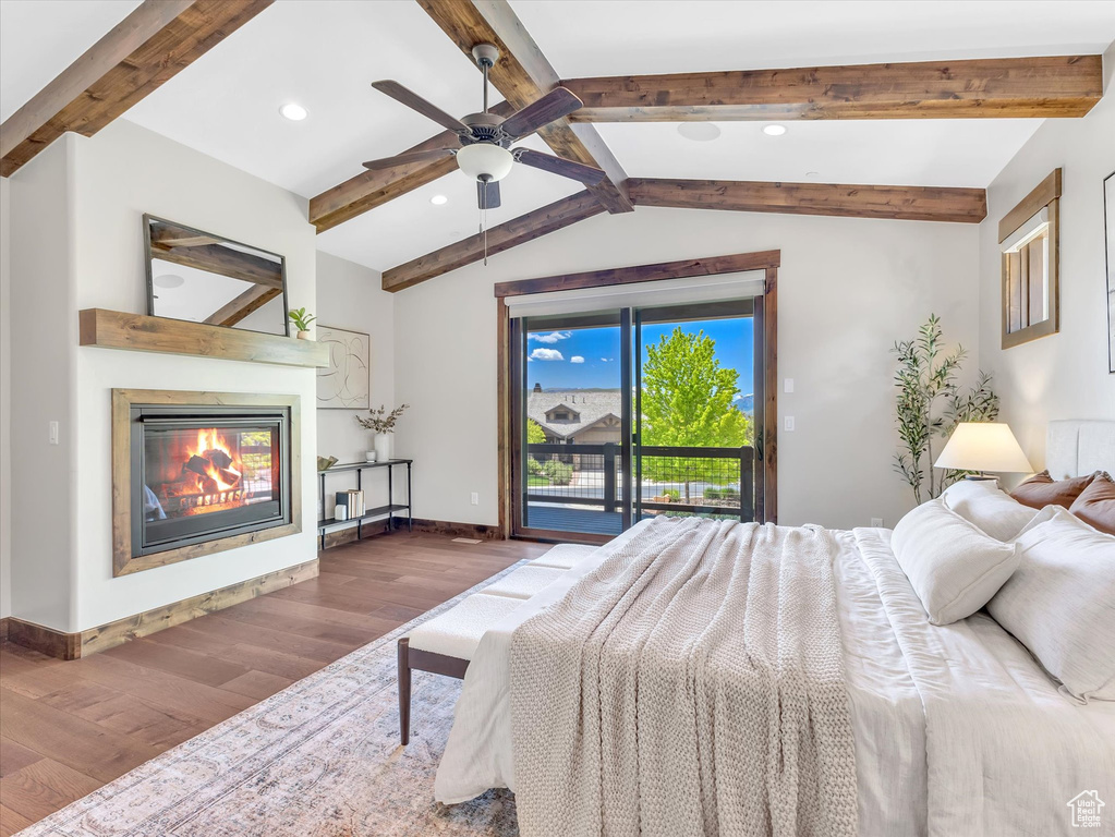 Bedroom featuring wood finished floors, access to outside, a glass covered fireplace, baseboards, and recessed lighting