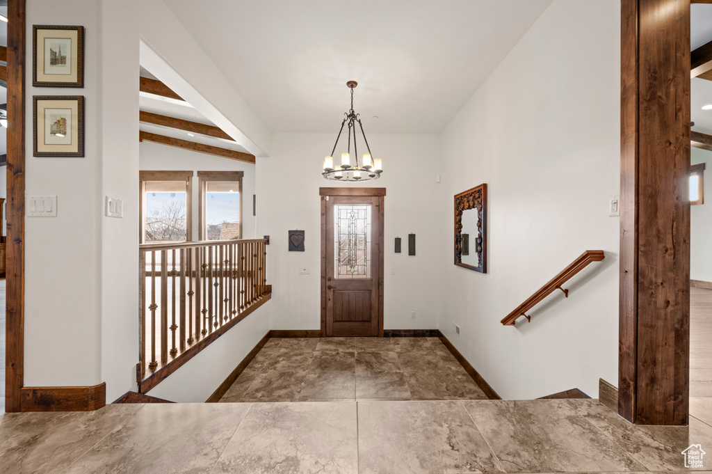 Entrance foyer with a notable chandelier, lofted ceiling with beams, and tile floors